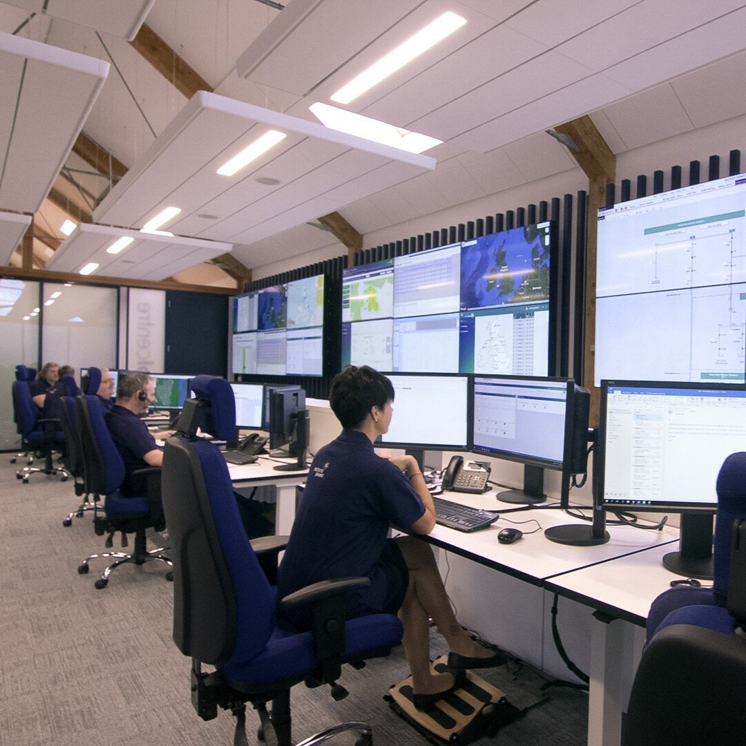 Multiple people in a control room sitting down and staring at their computers