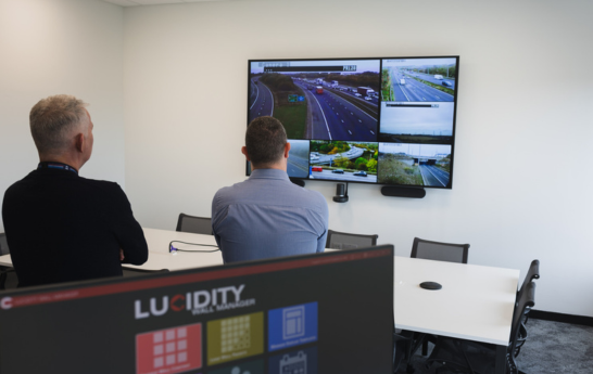 Two men looking at a screen in the conference room from an angled view with a screen in the corner