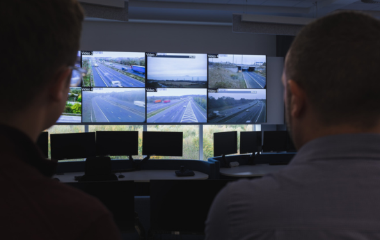 Two men looking at a video wall angled behind their heads