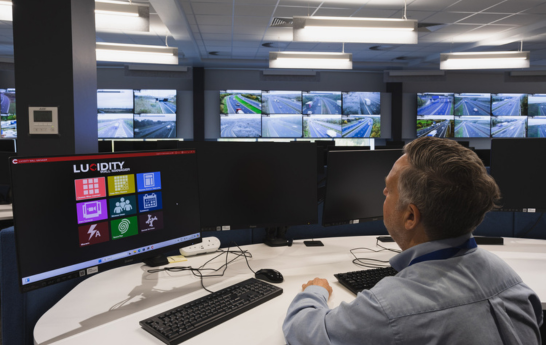 A man sitting down at his desk looking over the monitors to view the video wall