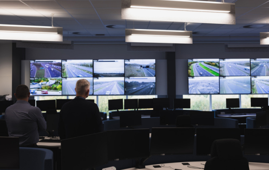 Two blurred men staring at the video wall from the left side of the room